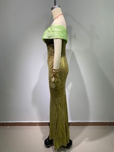 a mannequin wearing a green dress in front of a white wall