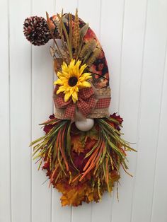 a wreath with sunflowers and other fall decorations hanging on a white wooden door