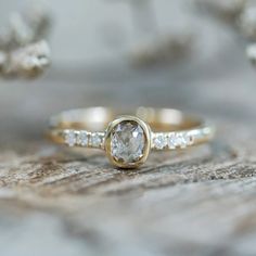 a close up view of a diamond ring on a piece of wood with other jewelry items in the background