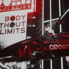 a red car parked in front of a tall building with the word body without limits on it