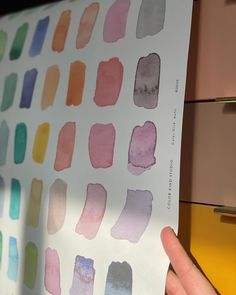 a person holding up a piece of paper with different colors on it