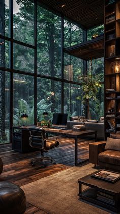 a living room filled with furniture and lots of glass walls that look out onto the woods