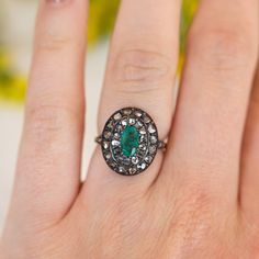 This antique Georgian ring features a .72 carat emerald and accent diamonds in two-tone 14 karat yellow gold and sterling silver. The oval cut emerald has a green-blue hue and is prong set in the center of an oval mounting. Thirty (30) accent diamonds halo the center emerald with six (6) accent diamonds decorating the shoulders of the band, set in sterling silver. From the profile, an openwork basket mounting holds the collection of gemstones finished on a polished and engraved 14 karat yellow g Heirloom Emerald-cut Ring With Single Cut Diamonds, Heirloom Emerald Cut Ring With Single Cut Diamonds, Oval Emerald Ring With Single Cut Diamonds, Oval Emerald Ring With Rose Cut Diamonds For Wedding, Oval Green Rose Cut Diamond Rings, Oval Emerald Ring With Rose Cut Diamonds, Heirloom Oval Emerald Ring With Single Cut Diamonds, Classic Oval Emerald Ring With Single Cut Diamonds, Oval Emerald Ring With Rose Cut Diamonds For Anniversary