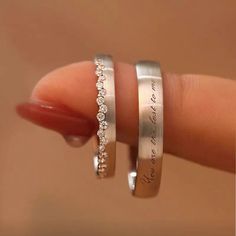 two silver rings with diamonds on them are being held by someone's hand in front of the camera