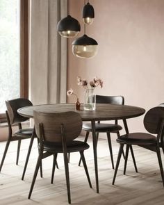 a dining table with four chairs and a vase filled with flowers