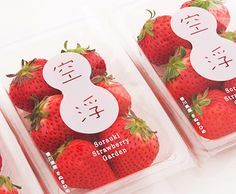 four plastic containers filled with strawberries on top of a table