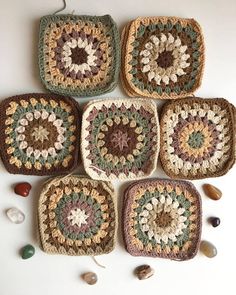 four crocheted grannys are arranged on the floor with rocks and stones around them