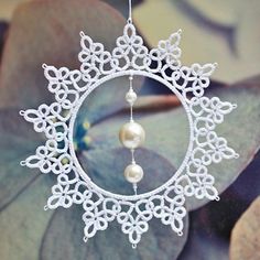 a white ornament with pearls hanging from it's side on a tree branch