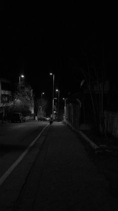 an empty street at night with no cars on it and one car parked in the dark