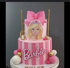 a barbie doll cake is decorated with pink and white stripes, gold trimmings, and a bow