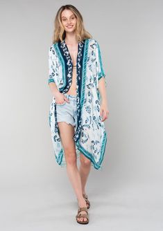 [Color: Ivory/Teal] A front facing image of a blonde model wearing a mid length bohemian kimono in an ivory and teal paisley and floral print. With half length kimono sleeves Bohemian Short Sleeve Kimono For Day Out, Blue Tunic Kimono For Spring, Bohemian Flowy Kimono With Short Sleeves, Flowy Bohemian Kimono With Short Sleeves, Bohemian Relaxed Fit Kimono For Daywear, Flowy Tunic Casual Kimono, Bohemian Short Sleeve Flowy Kimono, Casual Long Floral Print Kimono, White Boho Print Kimono For Spring