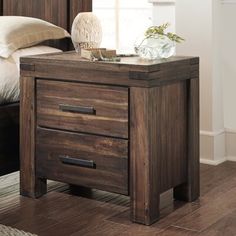 a wooden night stand with two drawers and a pillow on the bed next to it