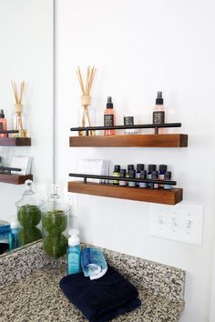 a bathroom counter with bottles and soaps on it next to two shelves above the sink