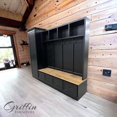 an empty room with wooden walls and black cabinets