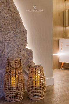 two vases sitting next to each other on top of a wooden floor in front of a stone wall