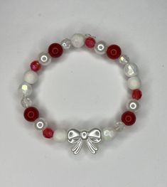 A red and white bow bracelet Cheap Beaded Bracelets For Christmas, Red Aesthetic Bracelet, White And Red Bracelets, Red Bracelets Aesthetic, Christmas Jewelry Aesthetic, Red And White Beaded Bracelet, White Jewelry With Decorative Bow For Party, White Jewelry With Decorative Bow For Gift, Party Jewelry With Decorative Bow In White