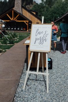 an easel with a sign that says love and jesus on it in front of some people