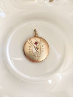 Beautiful antique gilt brass locket, set with two small stones in pink and clear glass. The colour of the locket appears to be slightly more rose gold on the pictures than in reality. The locket is nicely engraved.  The jewel is in overall good antique condition, but there are traces of wear due to its age: some scratches and traces of oxidation, especially on the sides and back. The locket closes well and looks very nice worn.  Dimensions: approx. 3.3 cm (with clasp) x approx. 2.5 cm diameter. Antique Gold Victorian Locket Jewelry, Rose Gold Vintage Charm Locket Necklace For Wedding, Victorian Locket Pendant Necklace With Vintage Charm, Vintage Rose Gold Locket Necklace For Wedding, Rose Gold Pendant Locket Jewelry, Rose Gold Locket Pendant Jewelry, Antique Pendant Locket Necklace With Vintage Charm, Antique Pendant Jewelry With Vintage Charm, Antique Rose Gold Necklace With Vintage Charm