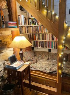 a laptop computer sitting on top of a wooden desk under a stair case filled with books