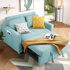 a blue couch sitting on top of a hard wood floor next to a potted plant