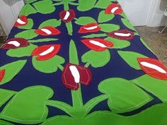 a bed covered in a blue and green bedspread with red flowers on it