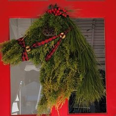 a red door with a horse head hanging from it's side and wreath on the front