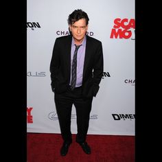 a man in a suit and tie standing on a red carpet at the scary movie premiere