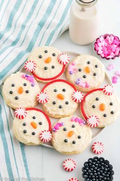 cookies decorated like snowmen on a plate next to candy canes and candies