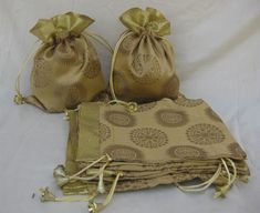 three bags are sitting next to each other on a white sheet with gold ribbon around them