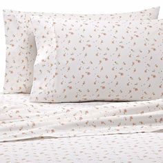 a bed with white sheets and orange flowers on it's headboard, in front of a white background