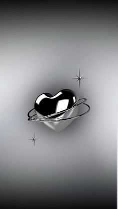 a black heart shaped object floating on top of a silver plate with stars in the background