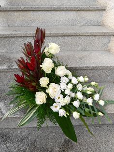 a bouquet of flowers sitting on top of some steps next to the stairs with red and white flowers