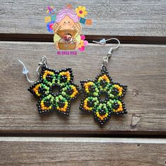 pair of beaded earrings with flower design on wooden table next to small magnets