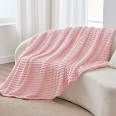 a pink blanket sitting on top of a white couch