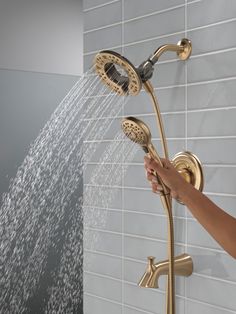 a person's hand is spraying water from a shower head