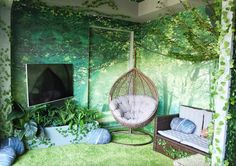 a living room with green walls and plants on the wall, hanging chair in front of tv