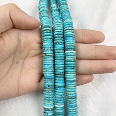 three turquoise beads are held in someone's hand