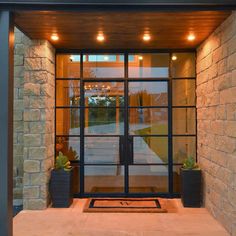 the front entrance to a modern home with glass doors and lights on it's sides