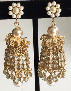 Here is a rare and absolutely dazzling pair of vintage earrings by designer Miriam Haskell. These earrings are exquisitely fashioned in an ultra glamorous chandelier style with multiple glittering strands of sparkling clear rhinestones with accents of bigger glimmering rhinestone drops at each swaying end. The shimmering strands are suspended on gold tone links from ornate crowns of glinting gold tone filigree and lustrous faux baroque pearls.The earring tops are made in a lovely floral motif... Vintage Dangle Chandelier Earrings For Anniversary, Vintage Chandelier Dangle Earrings For Anniversary, Vintage Chandelier Earrings For Anniversary, Vintage Dangle Chandelier Earrings For Festive Occasions, Vintage Gold Chandelier Earrings For Festive Occasions, Victorian Dangle Chandelier Earrings For Parties, Vintage Chandelier Dangle Earrings For Festive Occasions, Vintage Formal Filigree Chandelier Earrings, Victorian Chandelier Dangle Earrings For Party