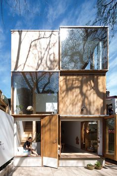 a person sitting on the ground in front of a house with wooden walls and windows