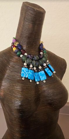 I created this one-off, bespoke beaded statement necklace from a recent sorting of my de-stash. This bold and chunky, colorful necklace contains the following components: blue crazy lace agate, rose encased lampwork beads, rhinestone balls, recycled blue-green African glass beads, emerals, sapphire, chevton amethyst, faceted crystals, jade, agate, purple freeform howlite nuggets and rhinestone rondelles. Adjusts from 15-18" and I can add additional links if requested. Closes with silver tone har Artisan Blue Beaded Necklaces, Unique Bib Necklace With Large Beads For Jewelry Making, Blue Large Beads Dangle Necklace, Blue Large Beaded Dangle Necklaces, Blue Large Beaded Dangle Necklace, Blue Beaded Dangle Necklace With Large Beads, Blue Dangle Beaded Necklace With Large Beads, Unique Turquoise Beaded Necklaces With Dangling Beads, Blue Beaded Dangle Necklaces With Natural Stones