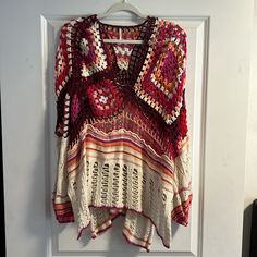 a crocheted sweater hanging on a white frame