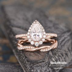 an engagement ring with a pear shaped diamond in the center on top of a rock