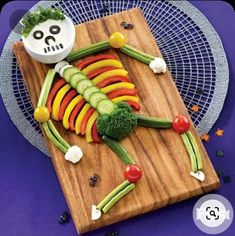 a wooden cutting board topped with vegetables on top of a table