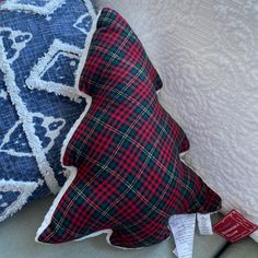 two pillows on a bed with price tags attached to the pillow and one has a plaid pattern