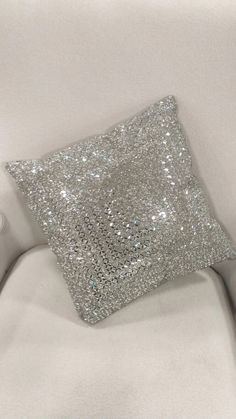 silver sequined pillow sitting on top of a white couch