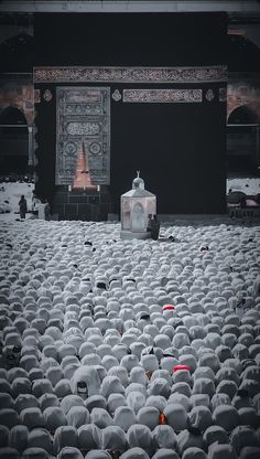 a large group of people standing in the middle of a room filled with white hats