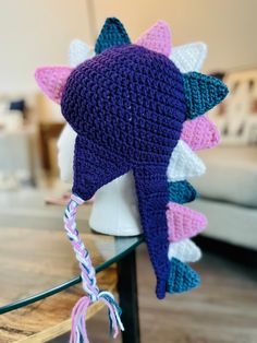 a crocheted hat with pink, white and blue spikes on it sitting on top of a table