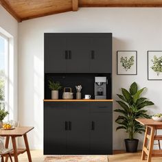 a kitchen with black cupboards and wooden table in the center, surrounded by potted plants