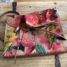 Classic leather Patricia Nash floral bag with shoulder straps. In excellent condition.Still has key for lock on bag.Also has extra matching accessory bag. Inside of bag is clean. No spills or tears.Very high end ,quality bag. Has two pockets on the outside.Will fit your cellphone.Inside divided into two sections .One side has a zippered pocket other side has two pockets. Sz. 14x10 3/4 in. The floral print includes red, yellow, green, orange, and pink on a  brown leather colored background. Leath Bag Inside, Floral Bags, Colored Background, Motorcycle Model, Orange And Pink, Matching Accessories, Classic Leather, Green Orange, Red Yellow